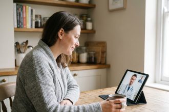Femme utilisant une tablette pour une consultation médicale en télémédecine depuis sa cuisine